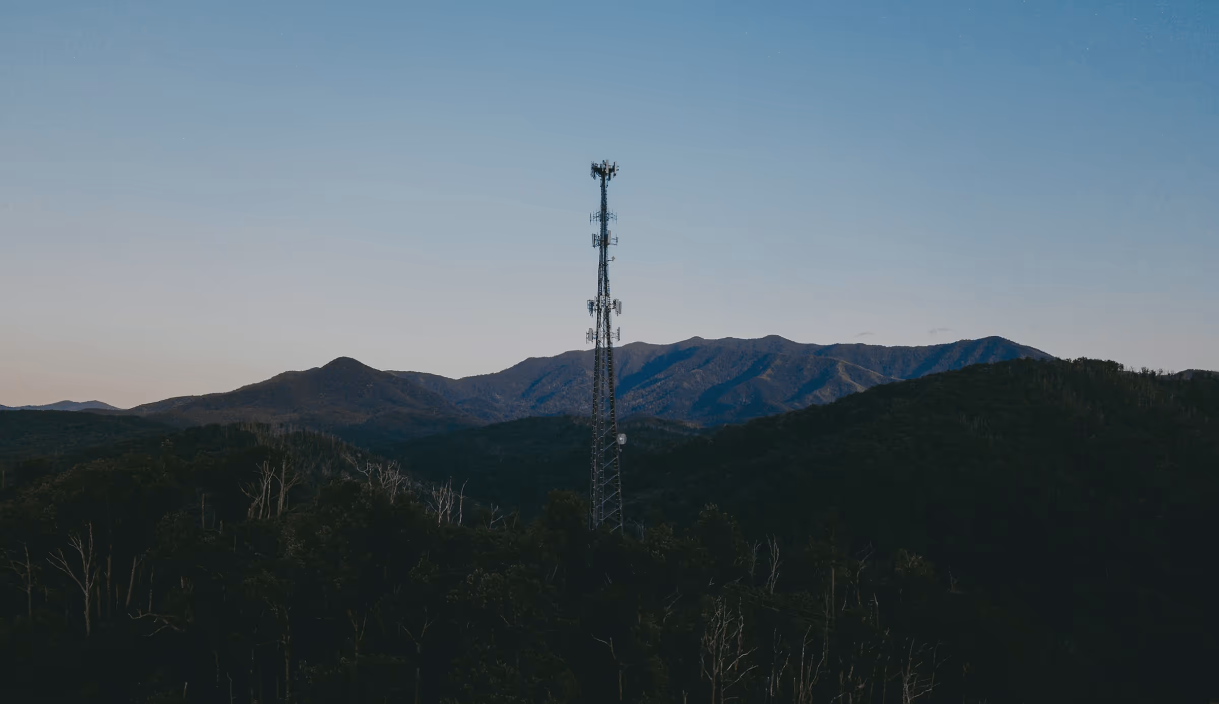 Mountainous landscape with a tall telecommunications tower under a clear blue sky, paired with the statement “Driven by purpose. Focused on the future.” representing Testudo’s commitment to securing global critical infrastructure through advanced communications, monitoring technology, and strategic expertise.