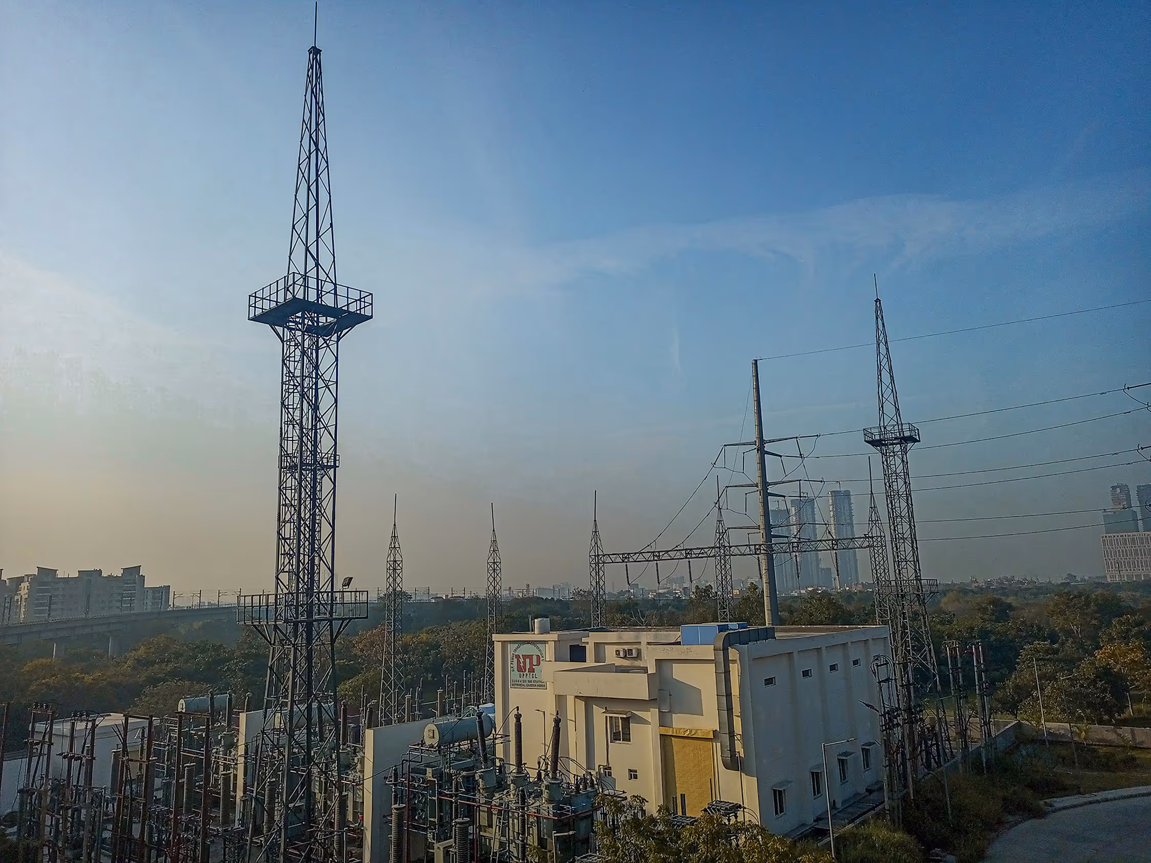 Electrical substation with steel transmission towers and power lines under a clear sky, illustrating operational challenges faced by utility companies and grid operators in maintaining reliable and secure energy infrastructure.