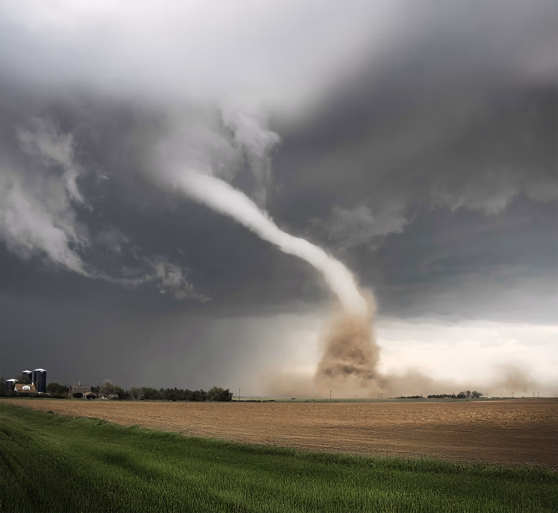 Powerful tornado touching down on open farmland under dark storm clouds, illustrating emergency management and national security challenges in natural disaster monitoring, preparedness, and response.