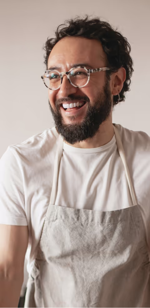 A bearded man smiling gently in a well-lit studio setting