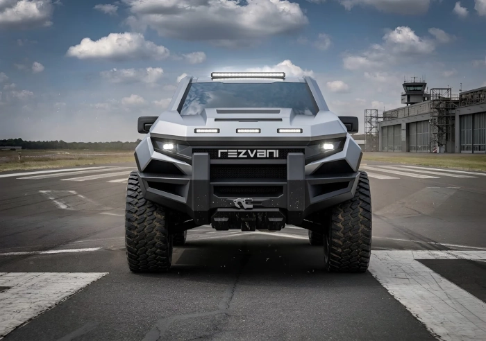 Detailní čelní pohled na drsný pickup Rezvani Fortress se svítícími LED světlomety a integrovaným navijákem v předním nárazníku.