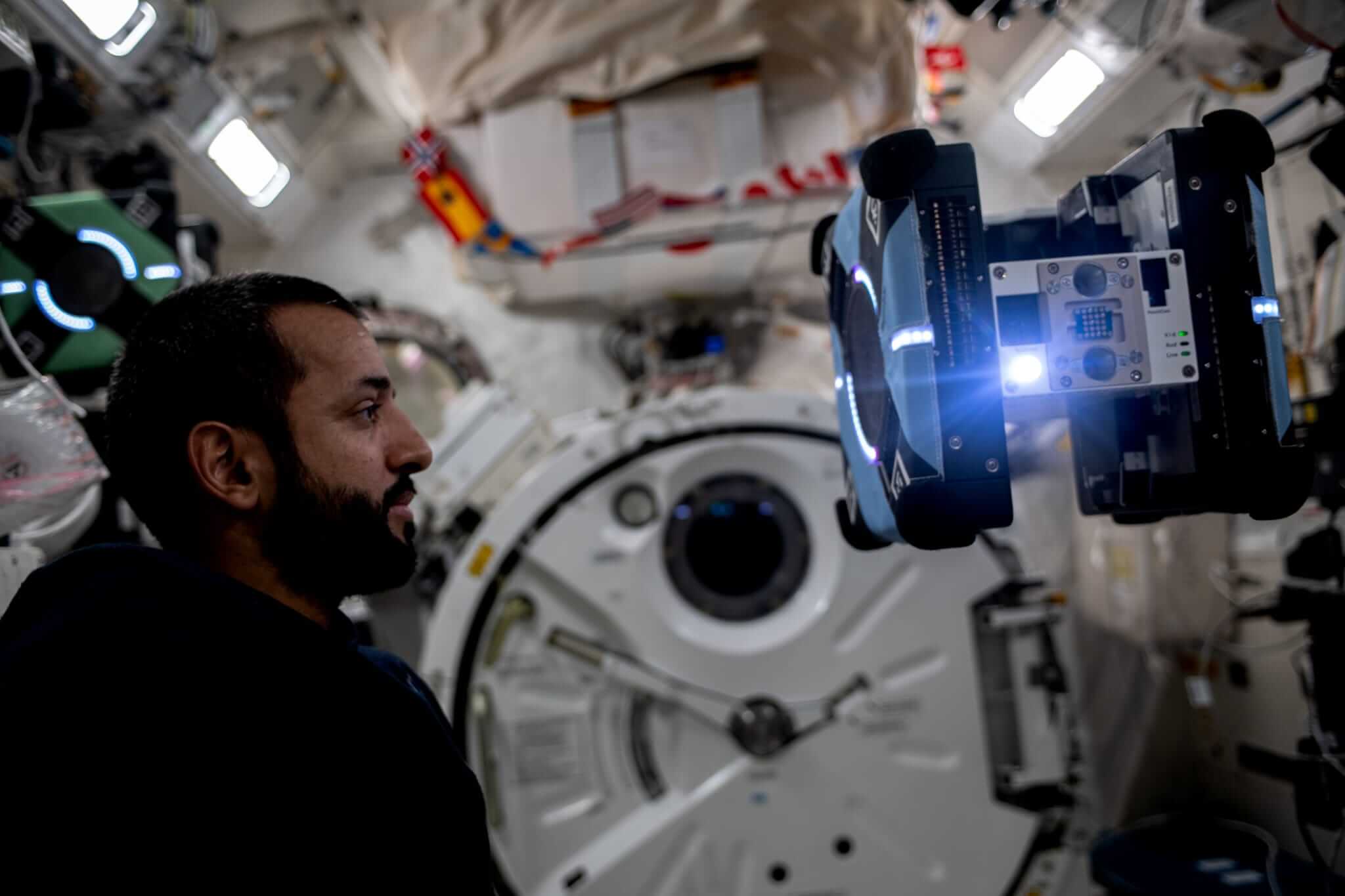 Astronaut ze Spojených arabských emirátů (SAE) a letový inženýr expedice 69 Sultan Alneyadi sleduje volně se vznášejícího robotického asistenta Astrobee během testování jeho funkcí v rámci připravované studentské soutěže v ovládání robotických zařízení.