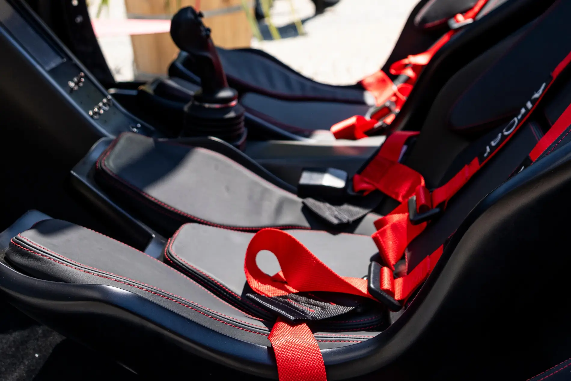 Detailní záběr na sportovní sedadla s červeným prošíváním a závodními bezpečnostními pásy uvnitř stroje AirCar.