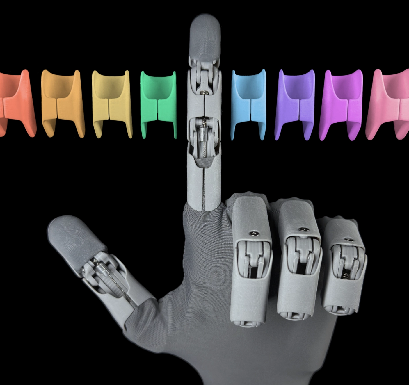 Robotická ruka HW1 a řada vyměnitelných 3D tištěných krytů v duhových barvách, která demonstruje možnosti přizpůsobení vzhledu.