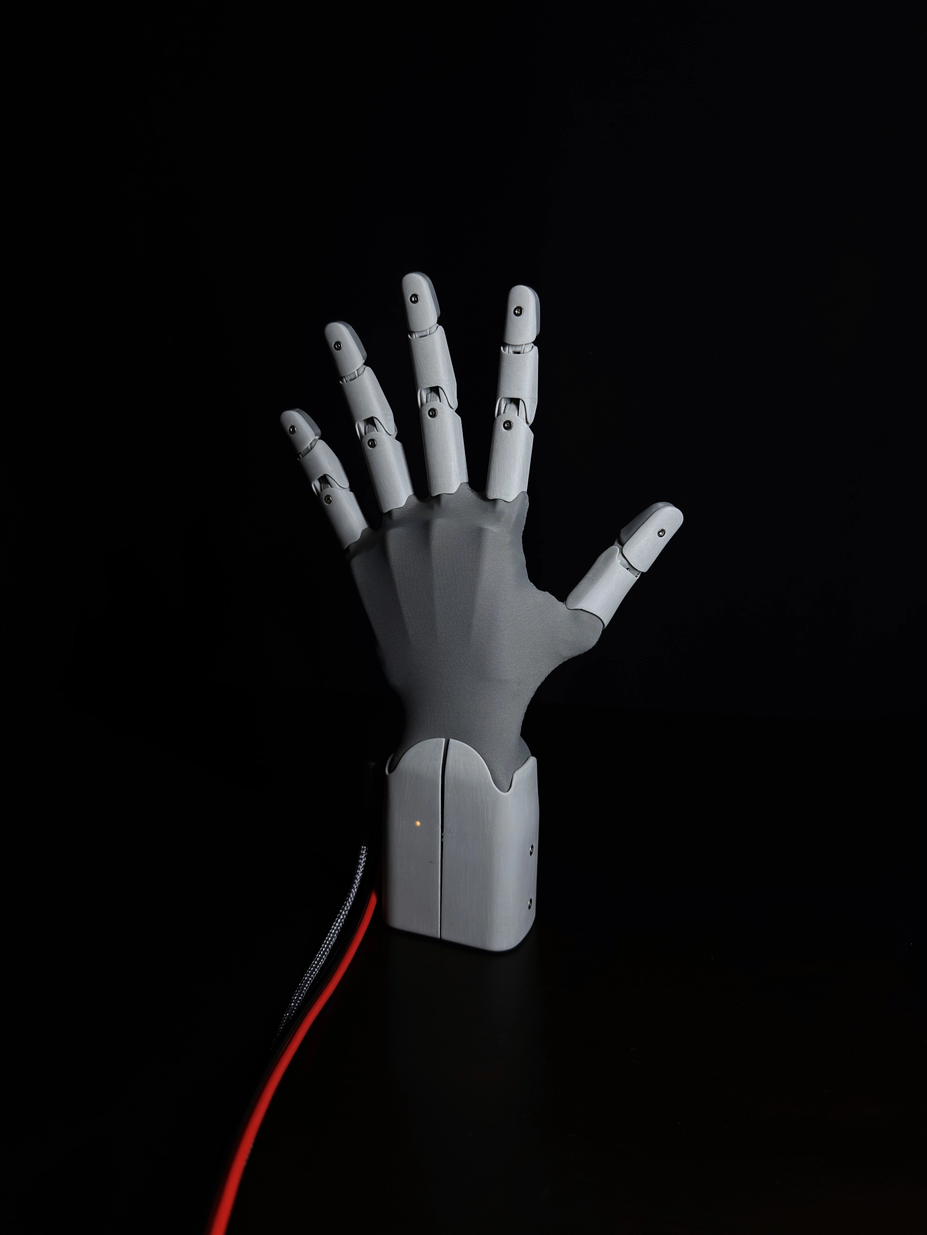 Robotická ruka HW1 s rozevřenými prsty z čelního pohledu na černém pozadí.