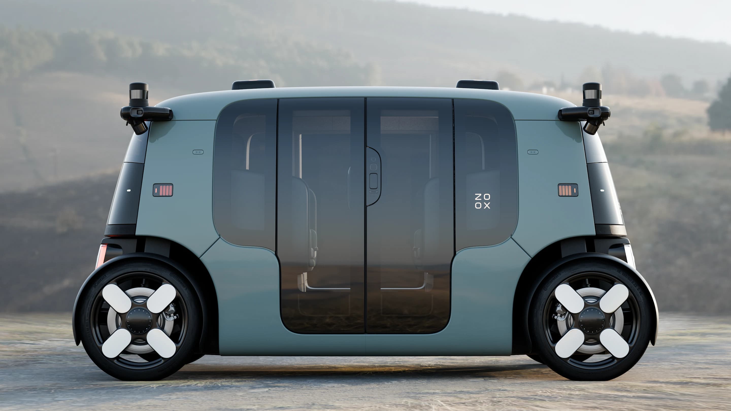 Kompletní pohled na bok robotaxi Zoox v aloe zelené barvě. Záběr v přírodní krajině zdůrazňuje jeho symetrický design, skleněné dveře a střešní senzory. 