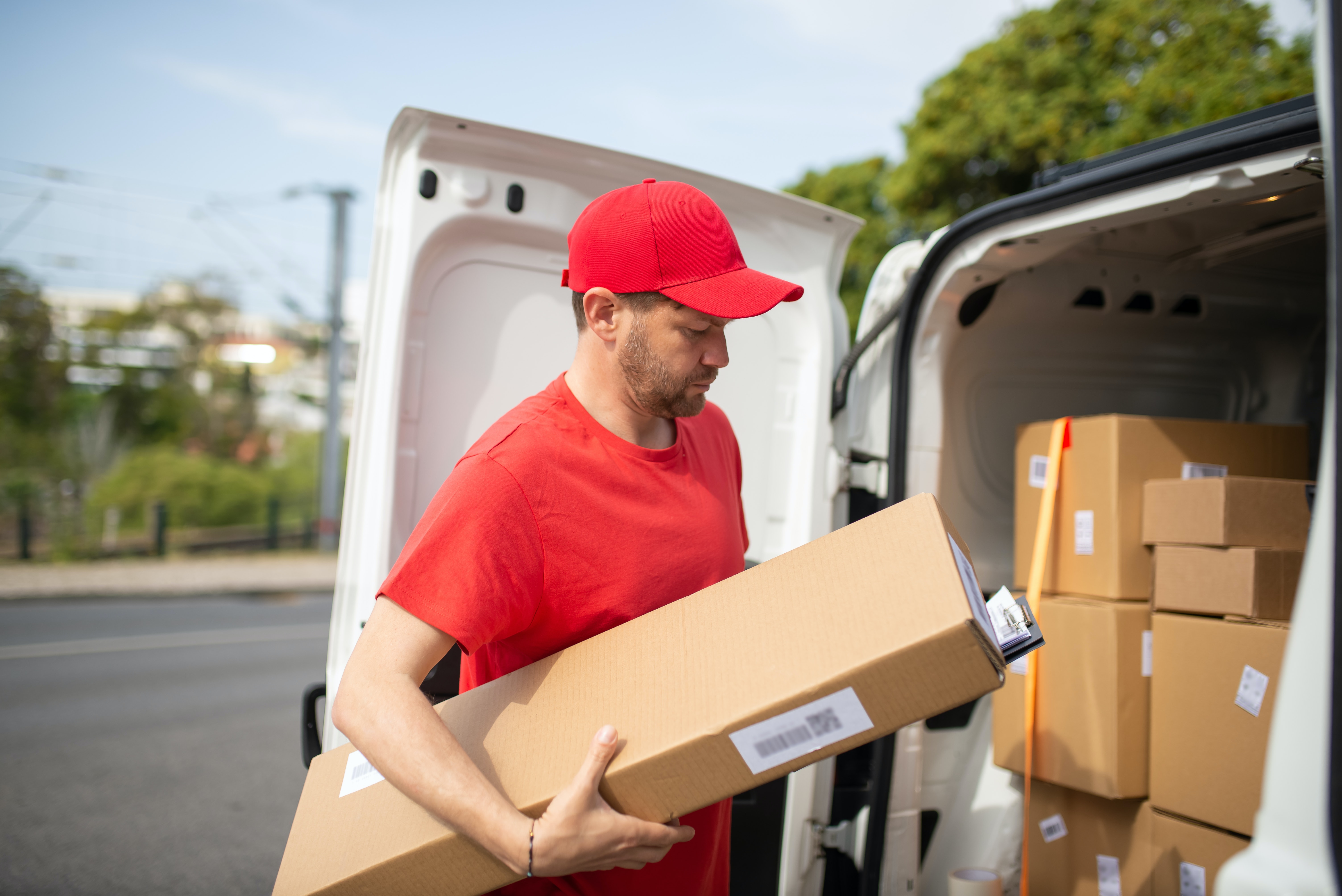 A delivery worker loads a package into a van