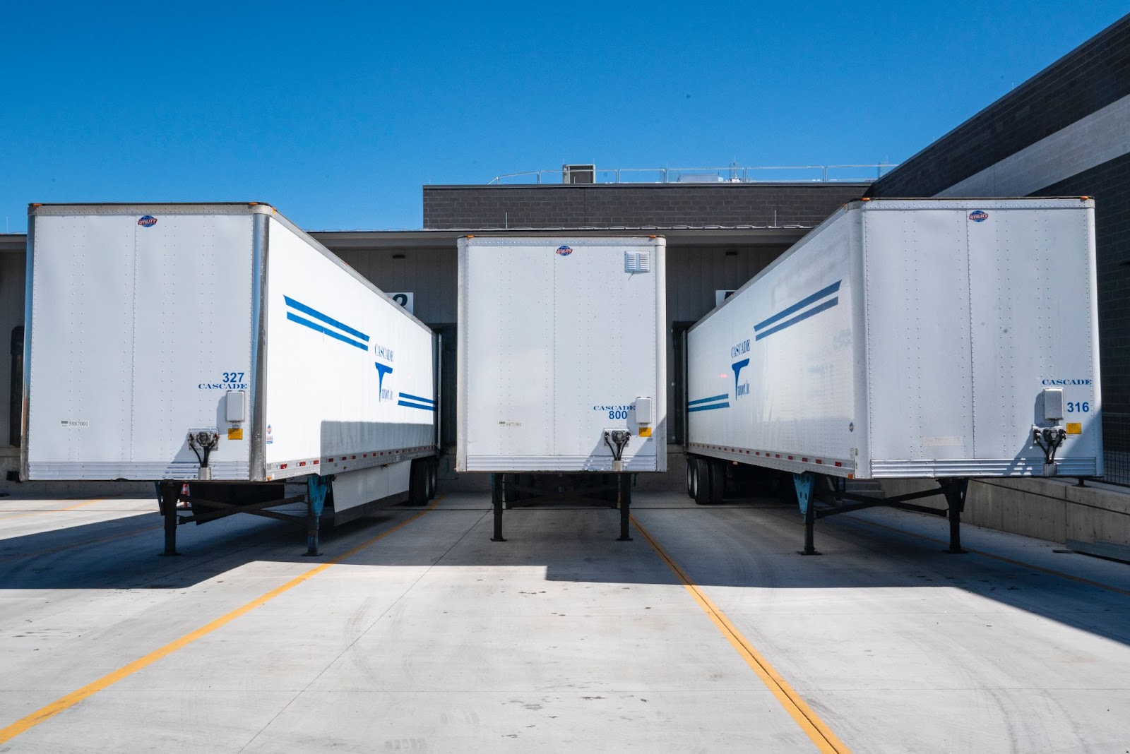 three delivery trucks are loaded at a 3PL warehouse