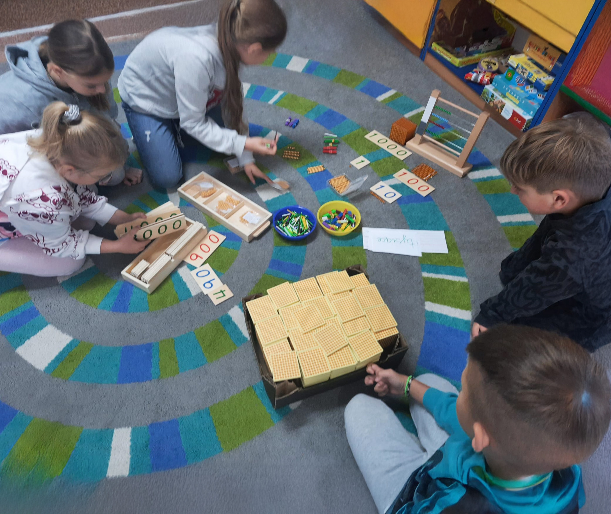 Dzieci robią obliczenia z wykorzystaniem małego liczydła