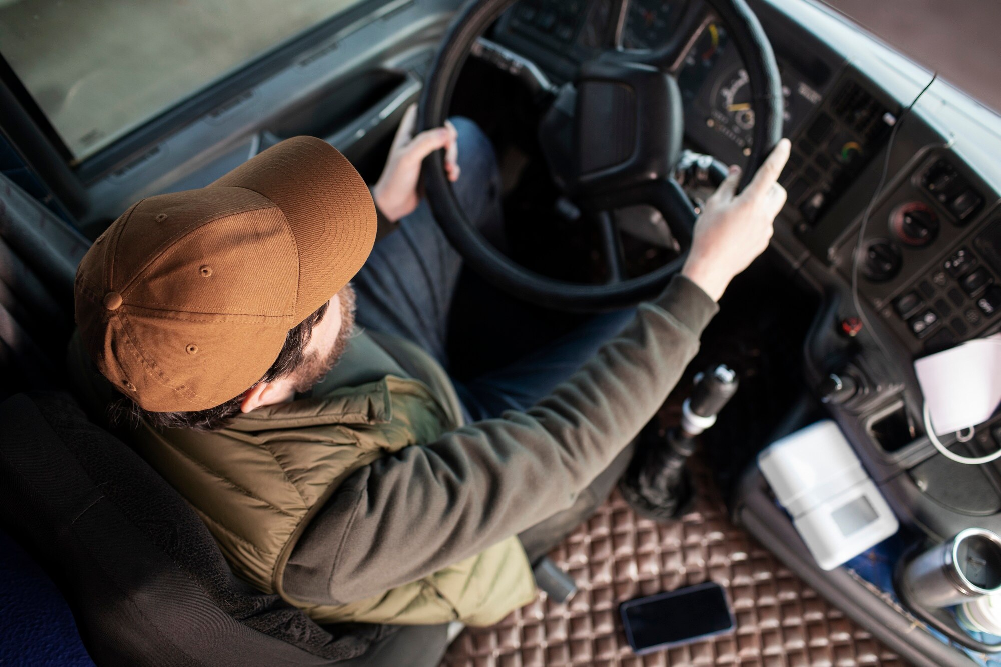 Truck driver inside cabin pointing at dashboard controls, representing Egala’s focus on safe, efficient, and professional trucking operations.