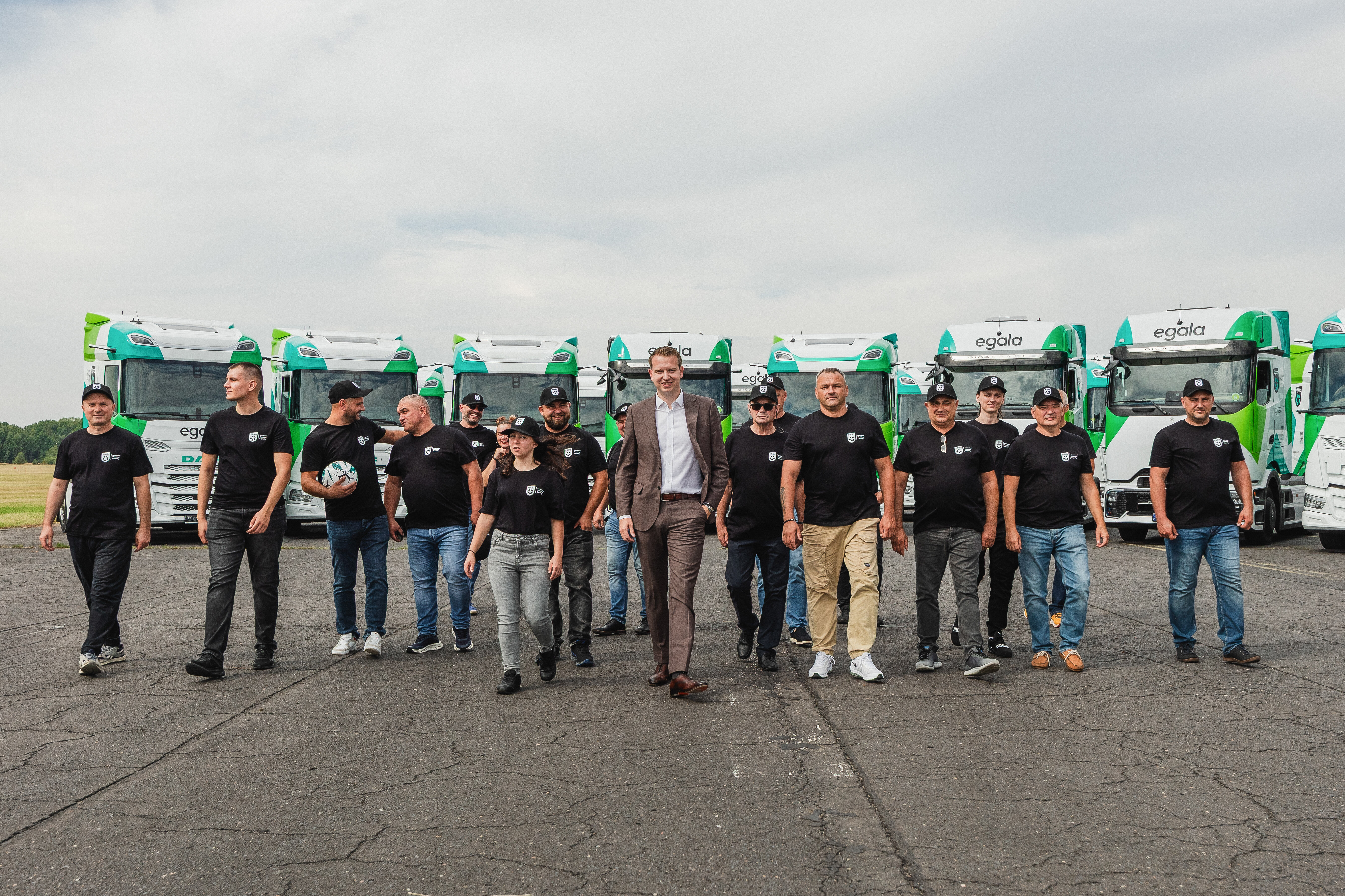 Egala trucking team and leadership standing in front of branded green and white trucks, representing reliable and sustainable trucking solutions.