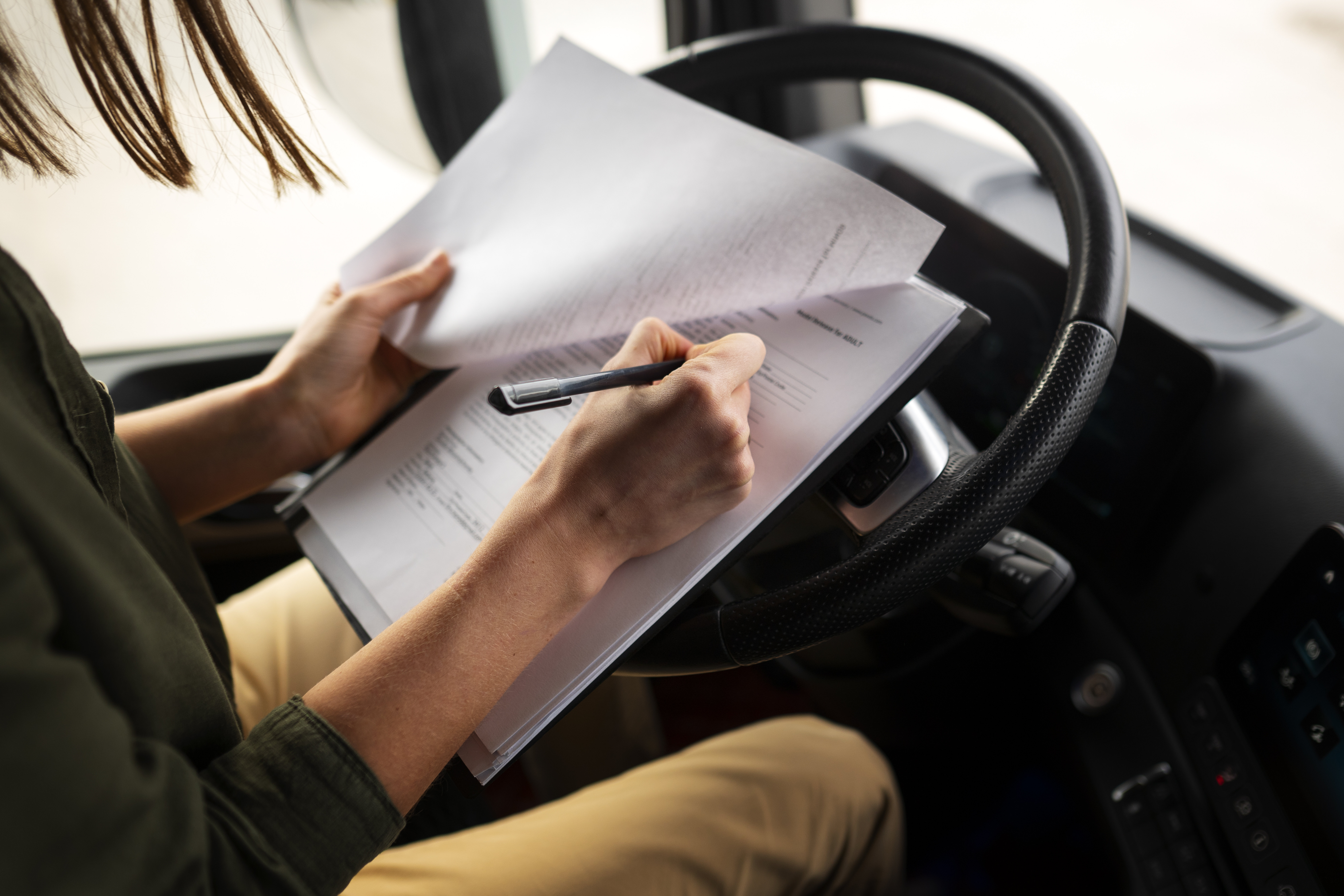 Driver reviewing logistics documents inside a truck cabin, illustrating manual paperwork challenges before adopting Egala by Boekestijn’s digital fleet solutions