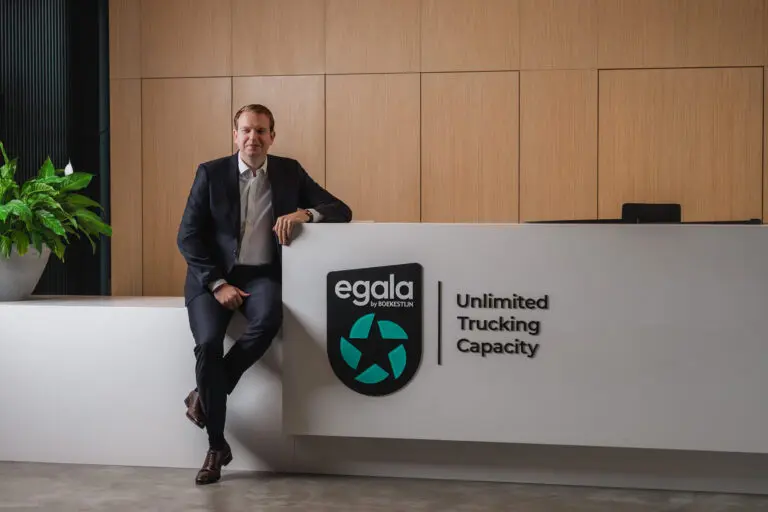 Sjef Boekestijn at Egala headquarters in front of the “Unlimited Trucking Capacity” sign, highlighting Egala’s European trucking services.