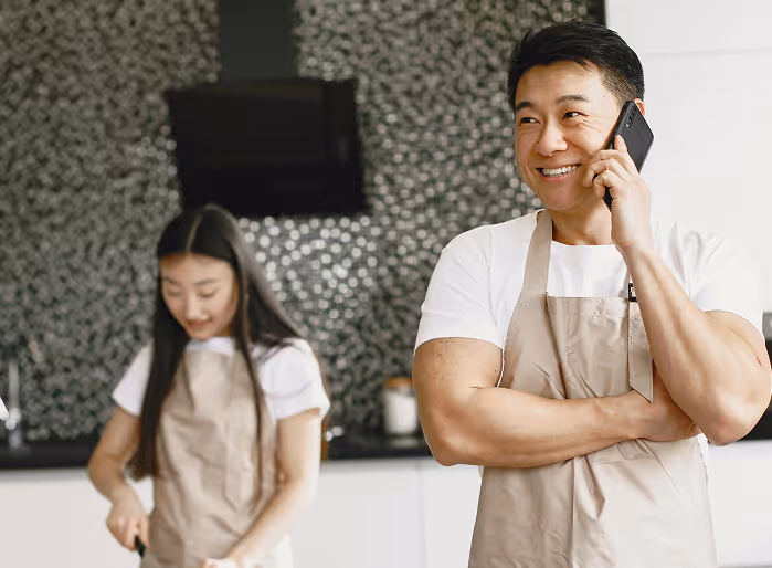 Two chefs one working another happily talking on phone