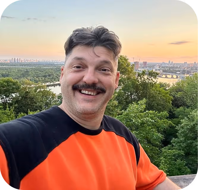 A man in an orange and black shirt is taking a selfie.
