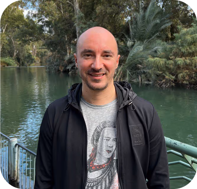 A bald man standing in front of a body of water.