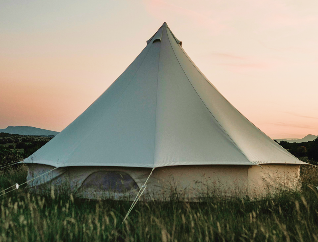 A large white tent sitting on top of a lush green field.