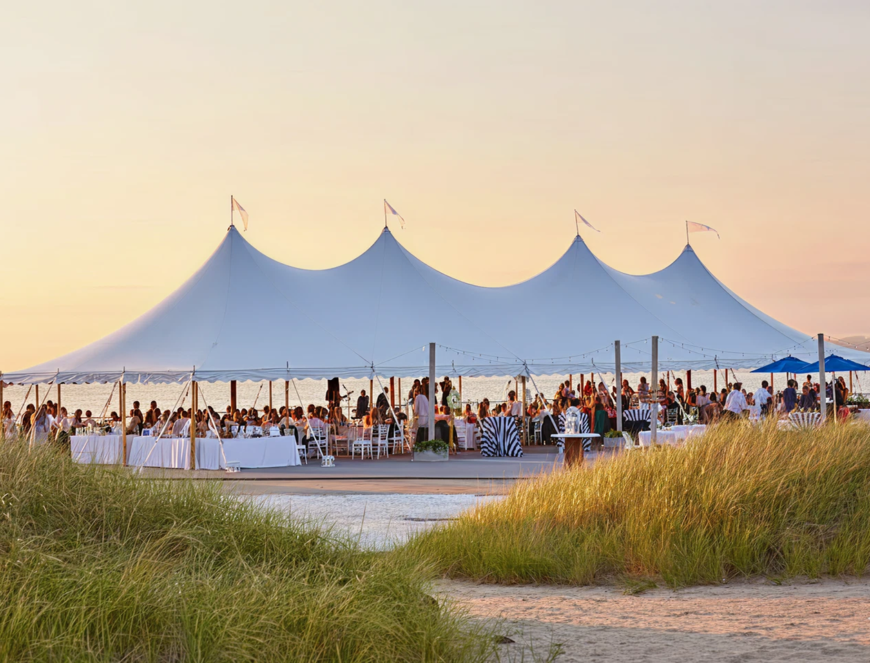 A large white tent sitting on top of a lush beach.