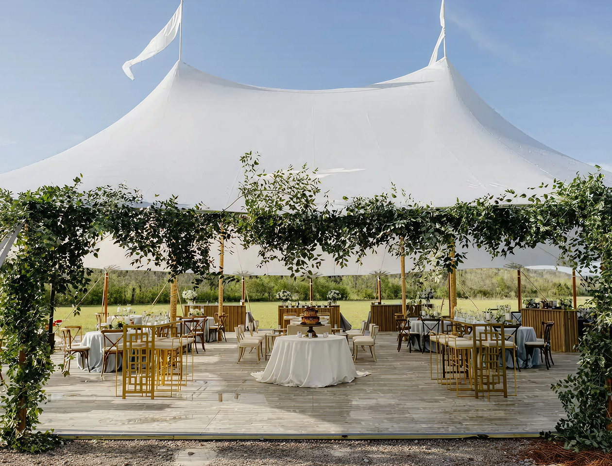 A large white tent with tables and chairs under it.