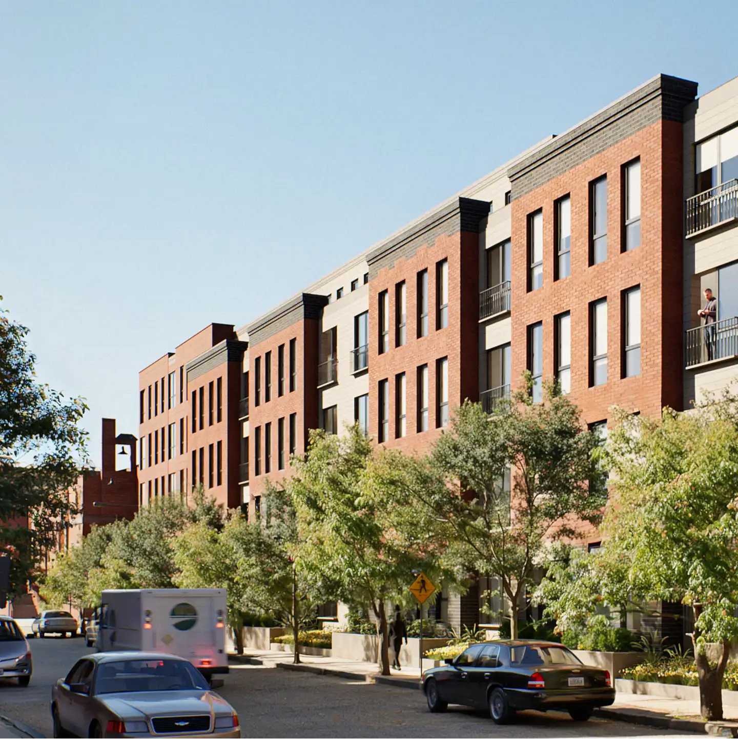 Daytime street view of a red-brick residential building lined with trees.
