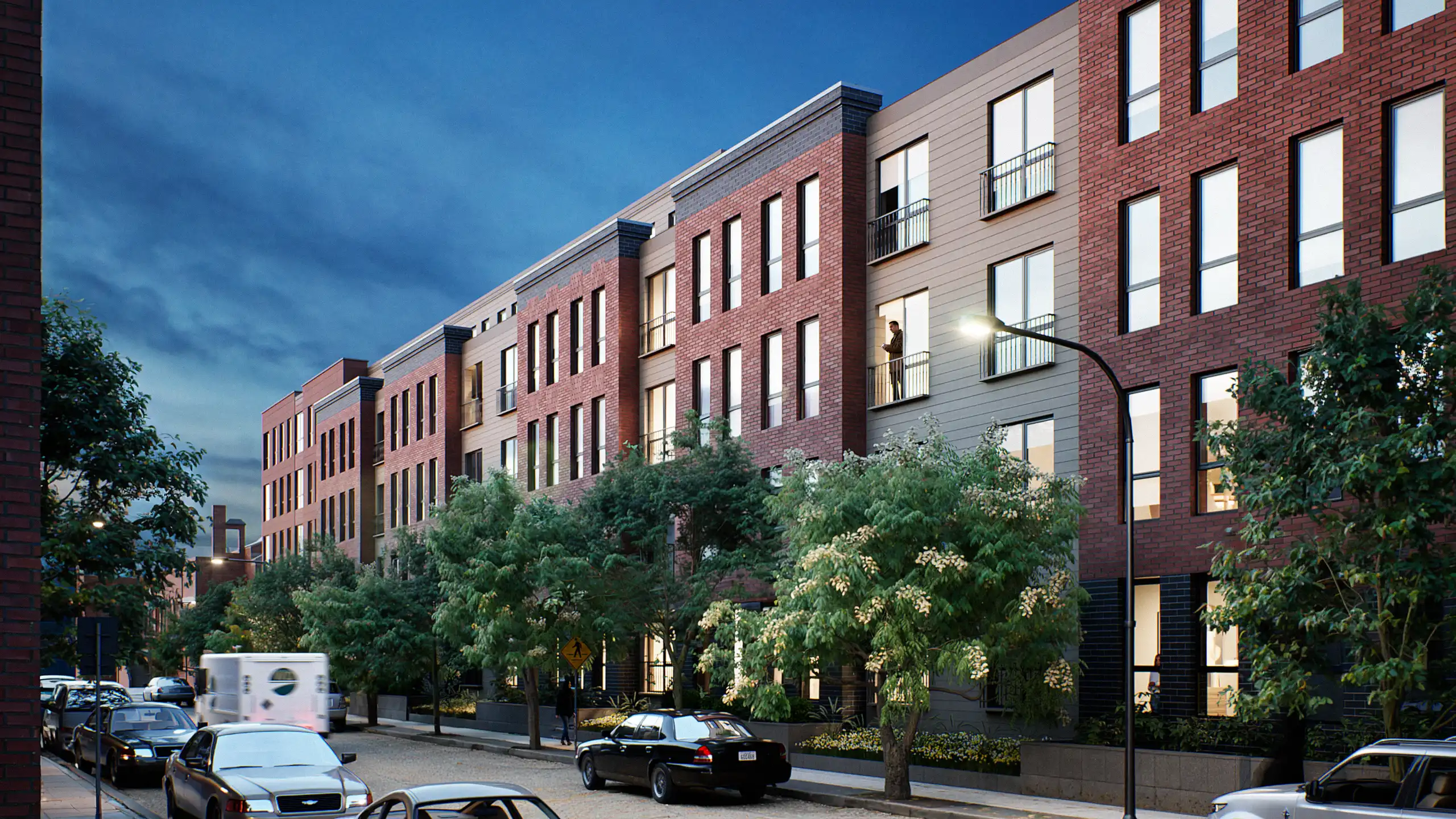 Nighttime view of a residential building facade illuminated along the street.
