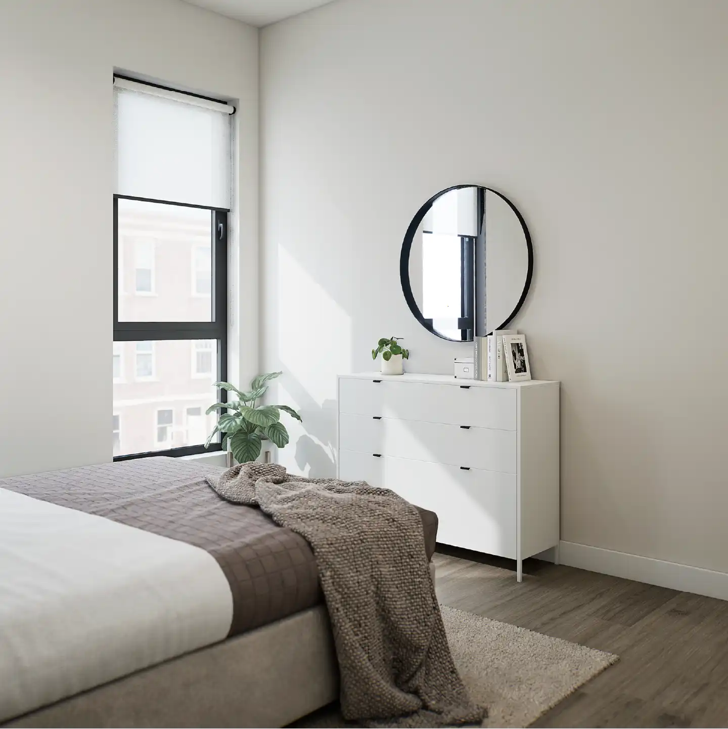 Bedroom corner with a white dresser, round mirror and soft natural lighting.