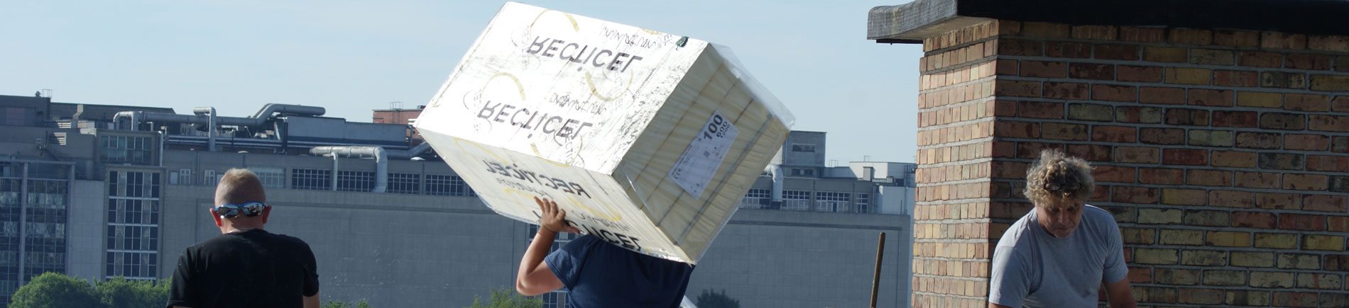 3 dakdekkers in beeld op een werf. Een dakdekker draagt allemaal roofing op zijn schouder
