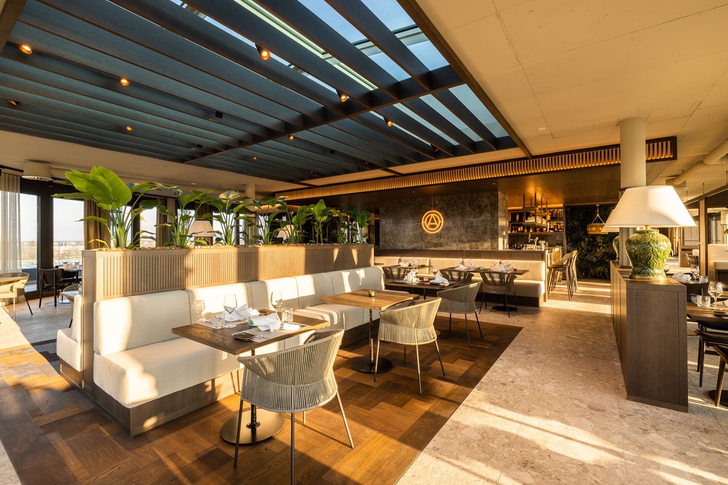 Elegantes Restaurant-Interieur mit Sitzecken, Tischen und Stühlen, warm beleuchtet für eine gemütliche Speiseatmosphäre.