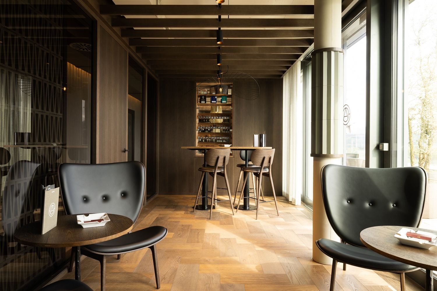Holztische und schwarze Lederstühle im Interieur eines modernen, trendigen Cafés.