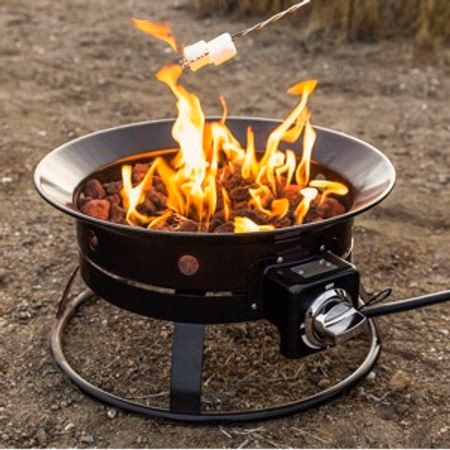 Outdoor fire pit with bright flames roasting a marshmallow on a stick over it.