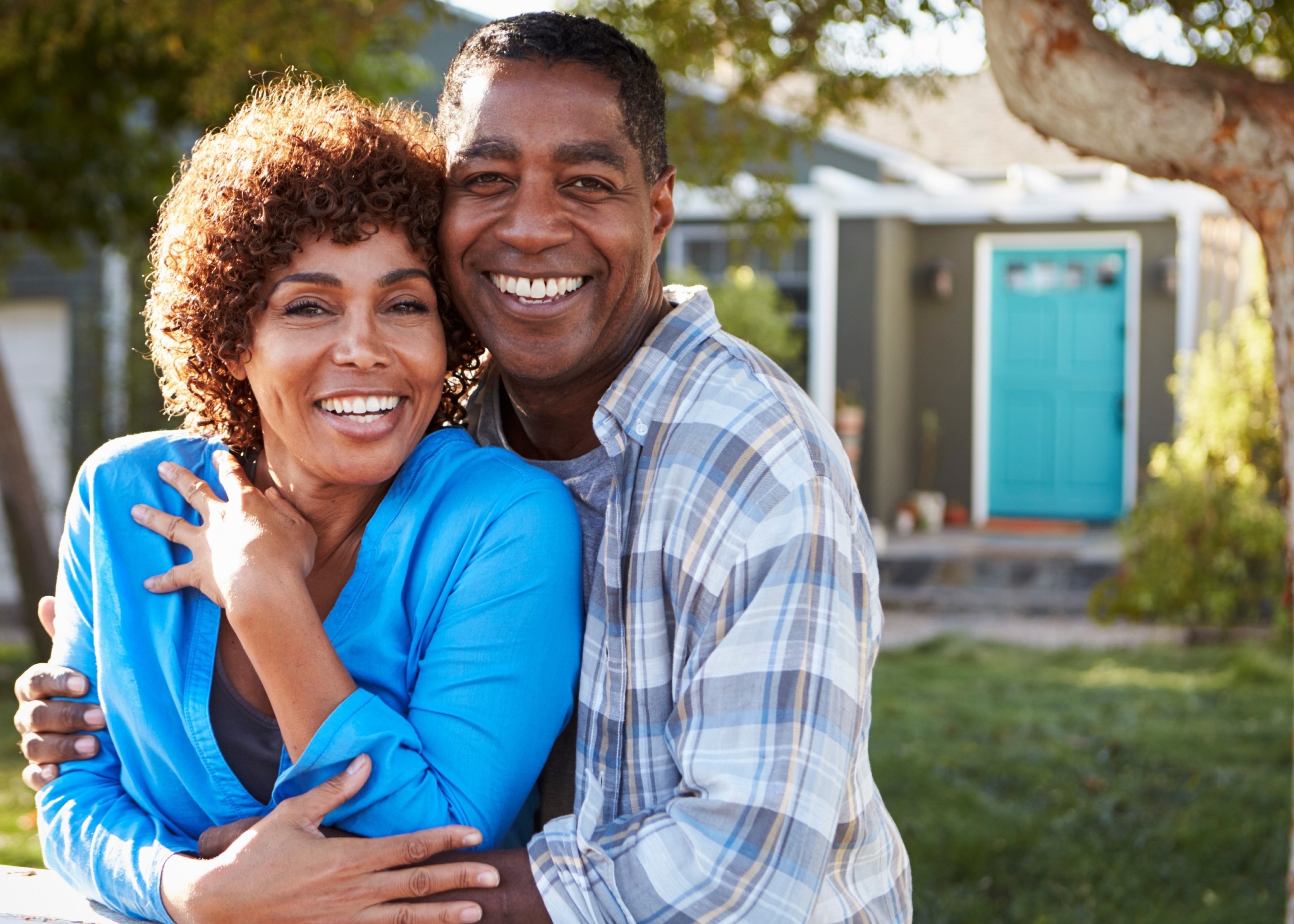 A man and woman hugging each other in front of a house.