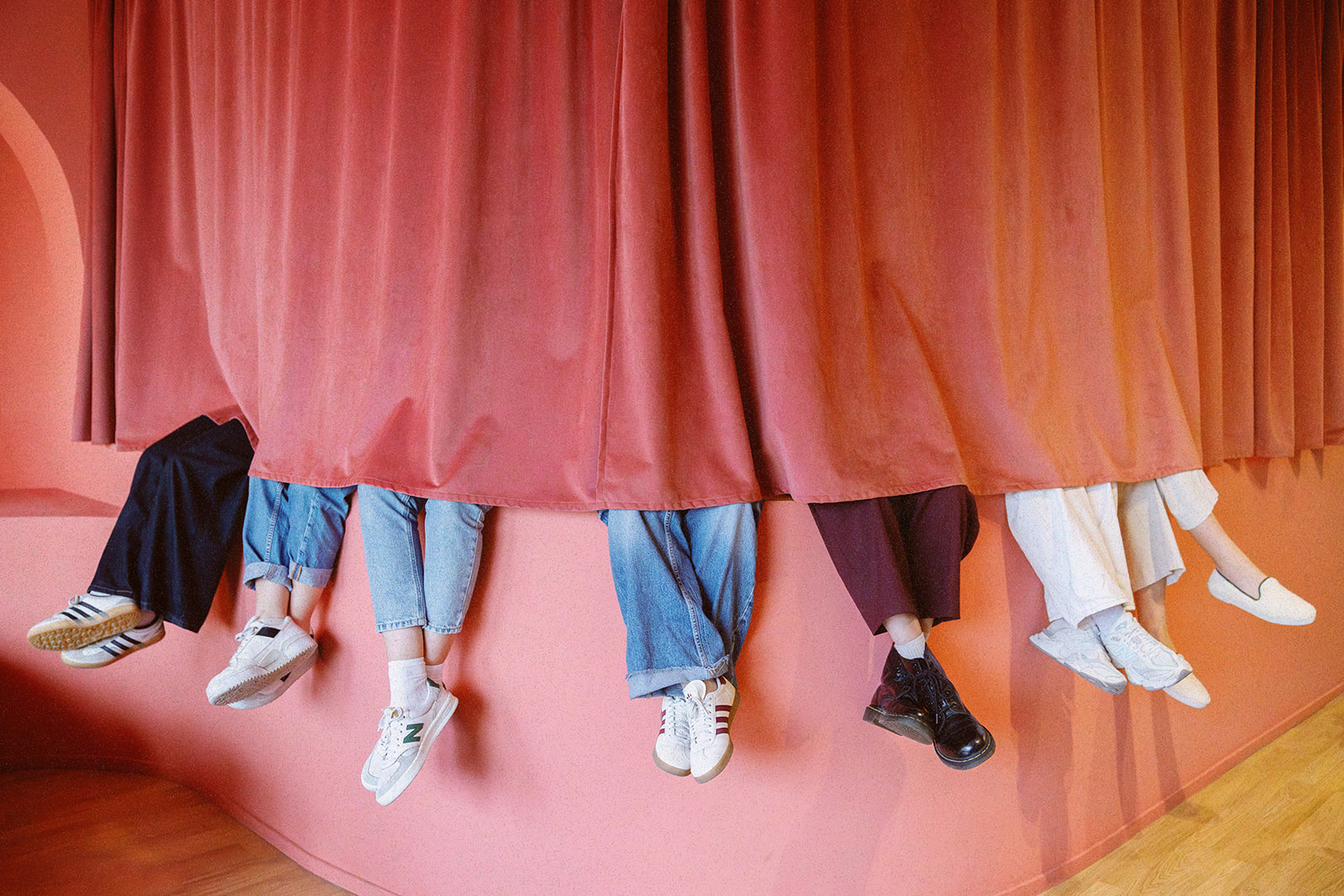 Artistic photography of the feet of the different team members sticking out from behind a curtain.
