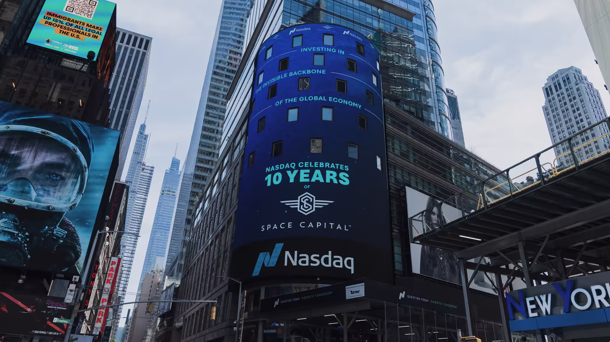 Nasdaq building in New York City displaying a large digital billboard celebrating Space Capital’s 10th anniversary, surrounded by skyscrapers and city traffic.