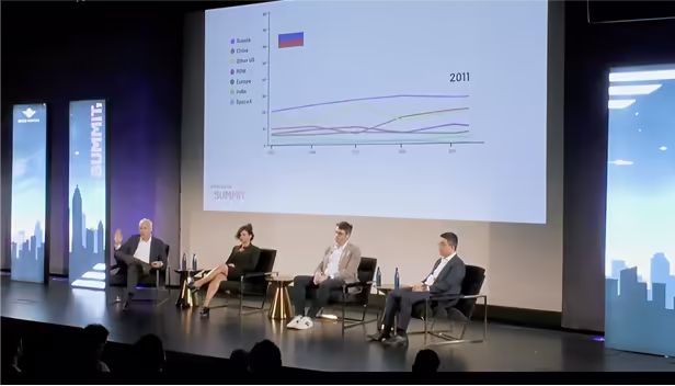 Panel of four speakers seated on stage during the Space Capital Summit, with a projected graph comparing global space activity by country behind them and an audience watching from the foreground.