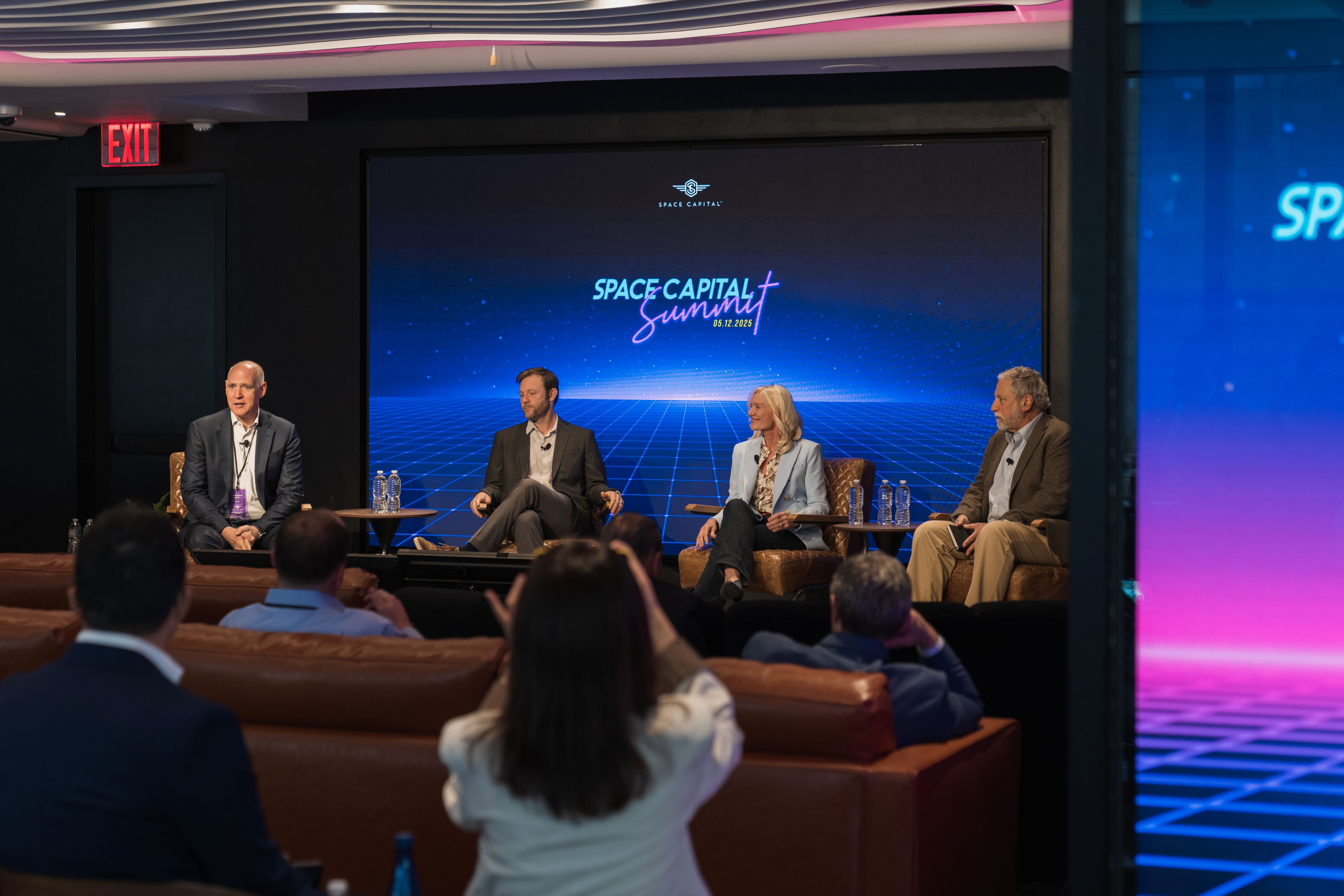 Panel of four speakers seated on stage during the Space Capital Summit.