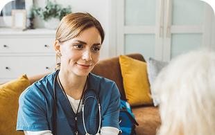 Healthcare professional in blue scrubs with stethoscope smiling in modern office setting.