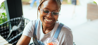 Smiling woman wearing glasses and light blue shirt indoors near window