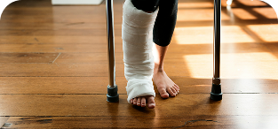 Person with bandaged foot standing on wooden floor with crutches