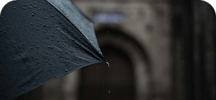 Close-up of open black umbrella with raindrops in rainy weather