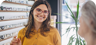 Woman wearing glasses and yellow shirt smiling in eyewear store