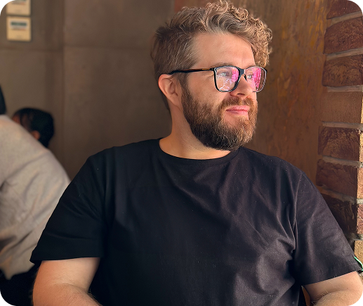 Man with glasses and beard wearing black t-shirt indoors