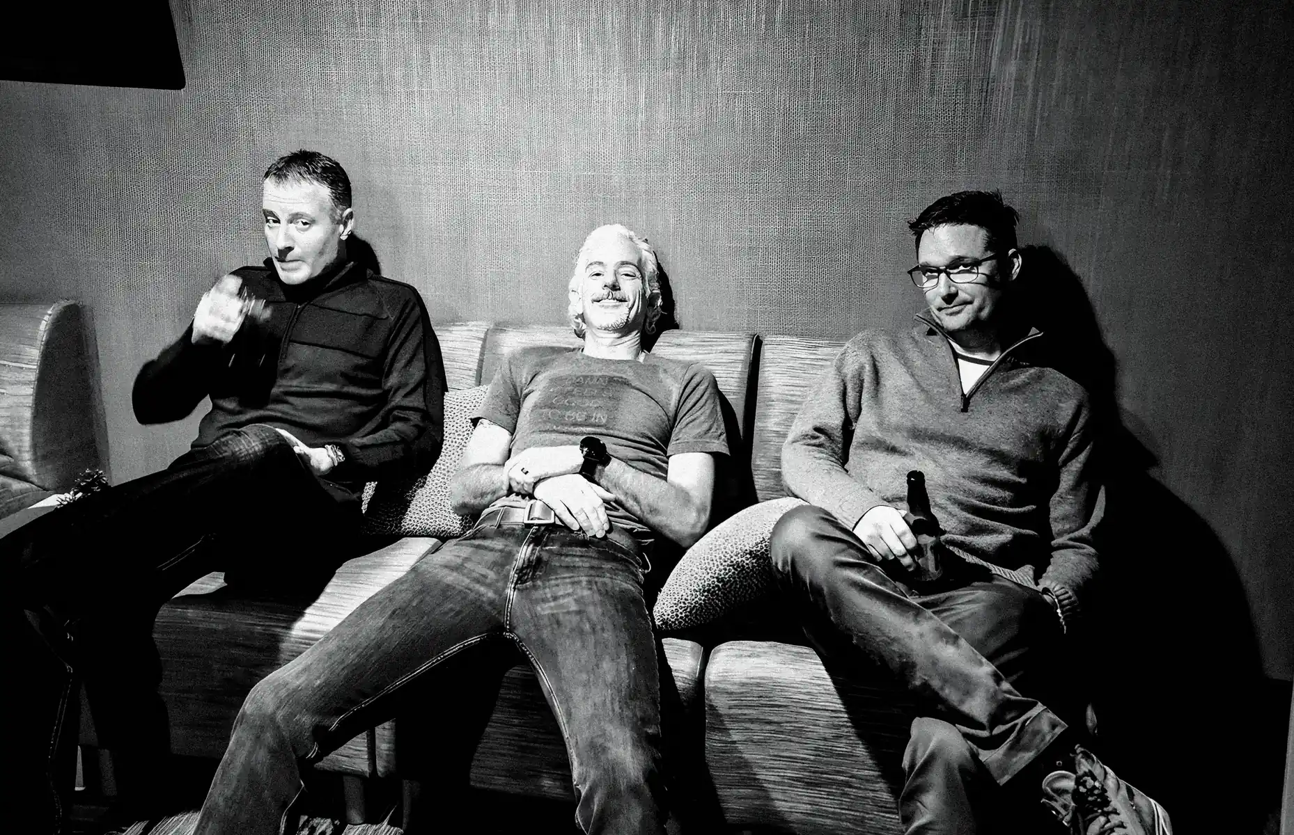 The three founders sitting on a couch together, exhausted, enjoying a beer.
