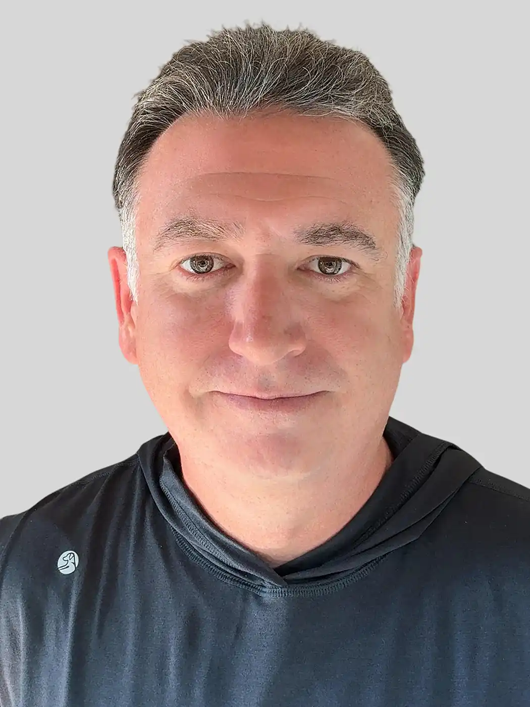A headshot of a man smiling with silver hair wearing a black shirt