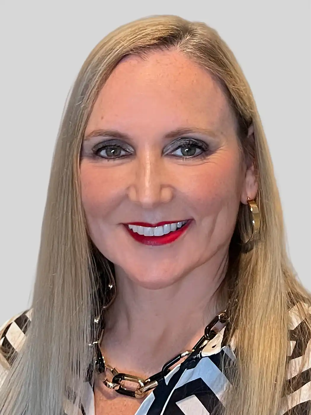 A headshot of a woman smiling with blonde hair wearing a striped top