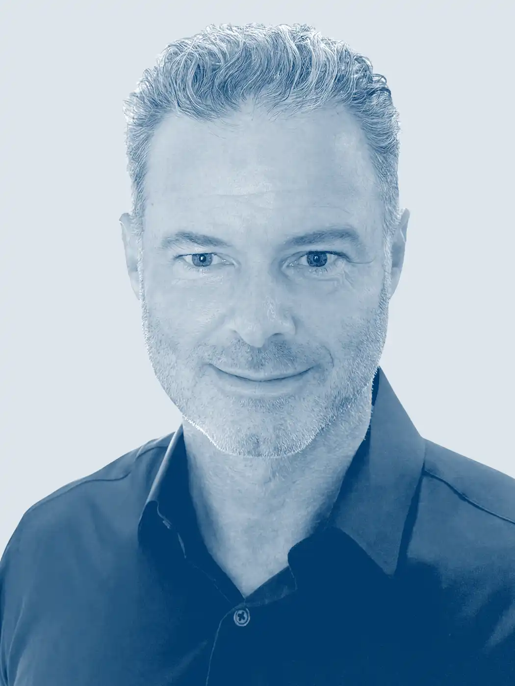 A headshot of a man smiling with silver hair wearing a dark blue button-up shirt with a blue overlay effect on the image