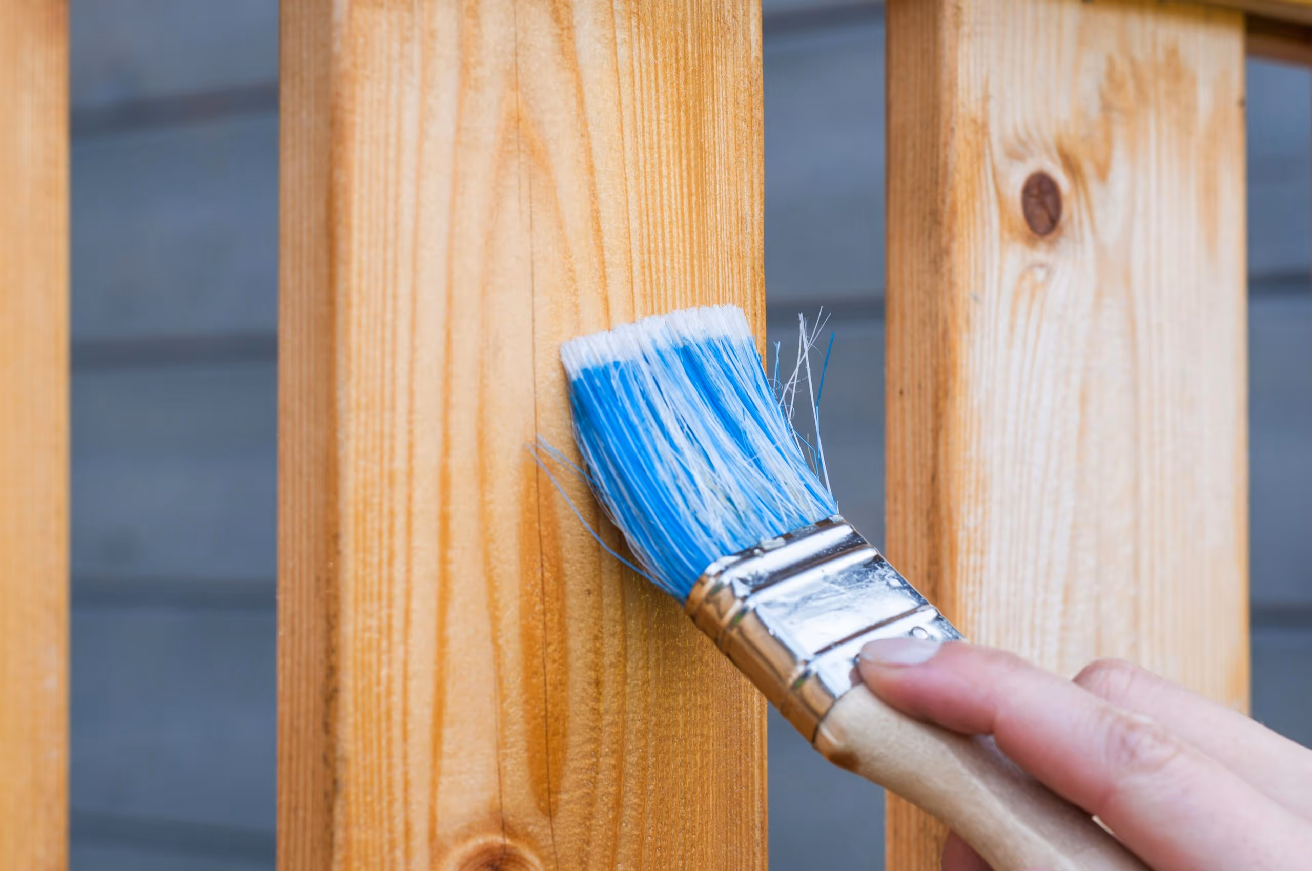 Paintbrush brushing against a wooden plank