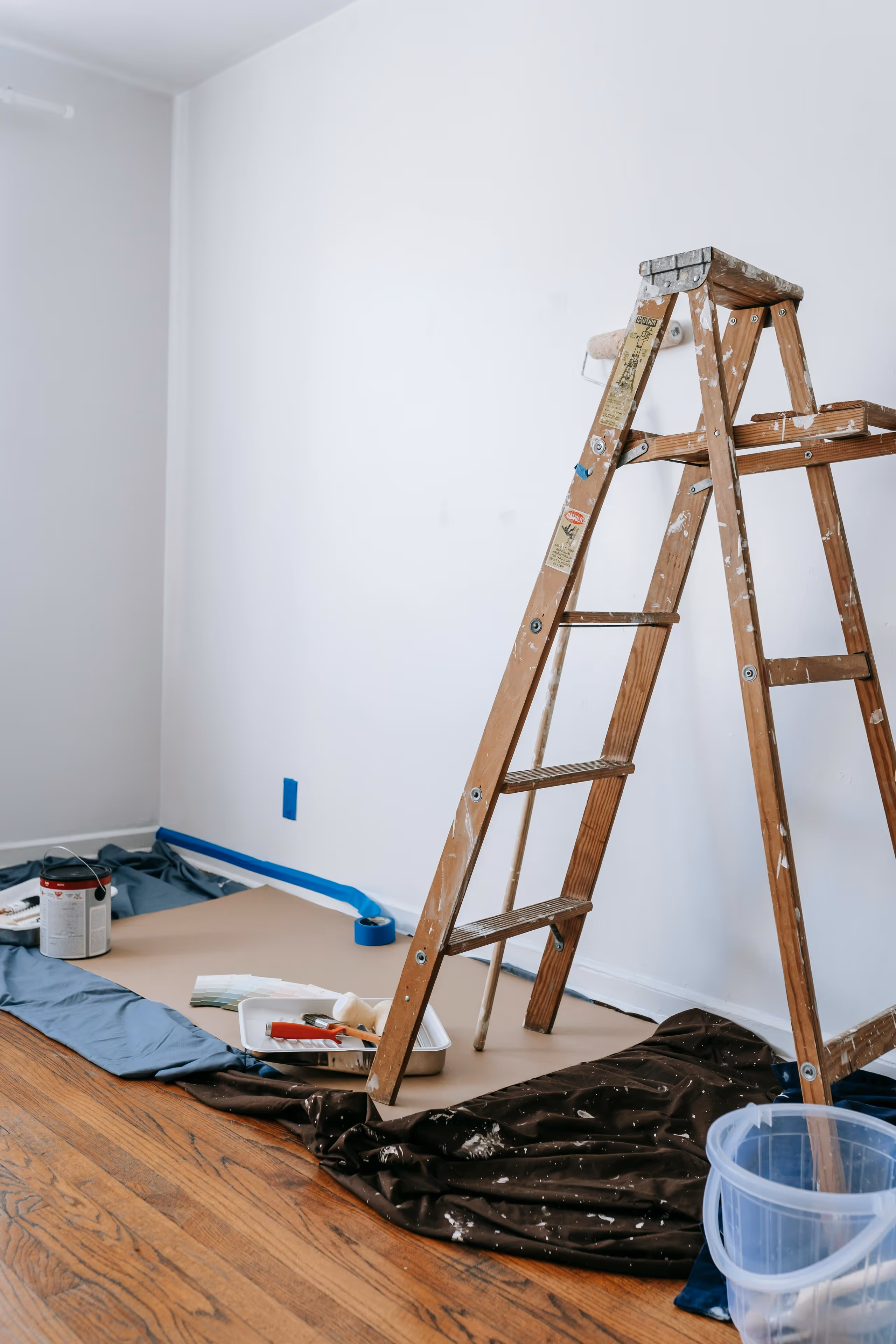 A wooden ladder next to a white wall.
