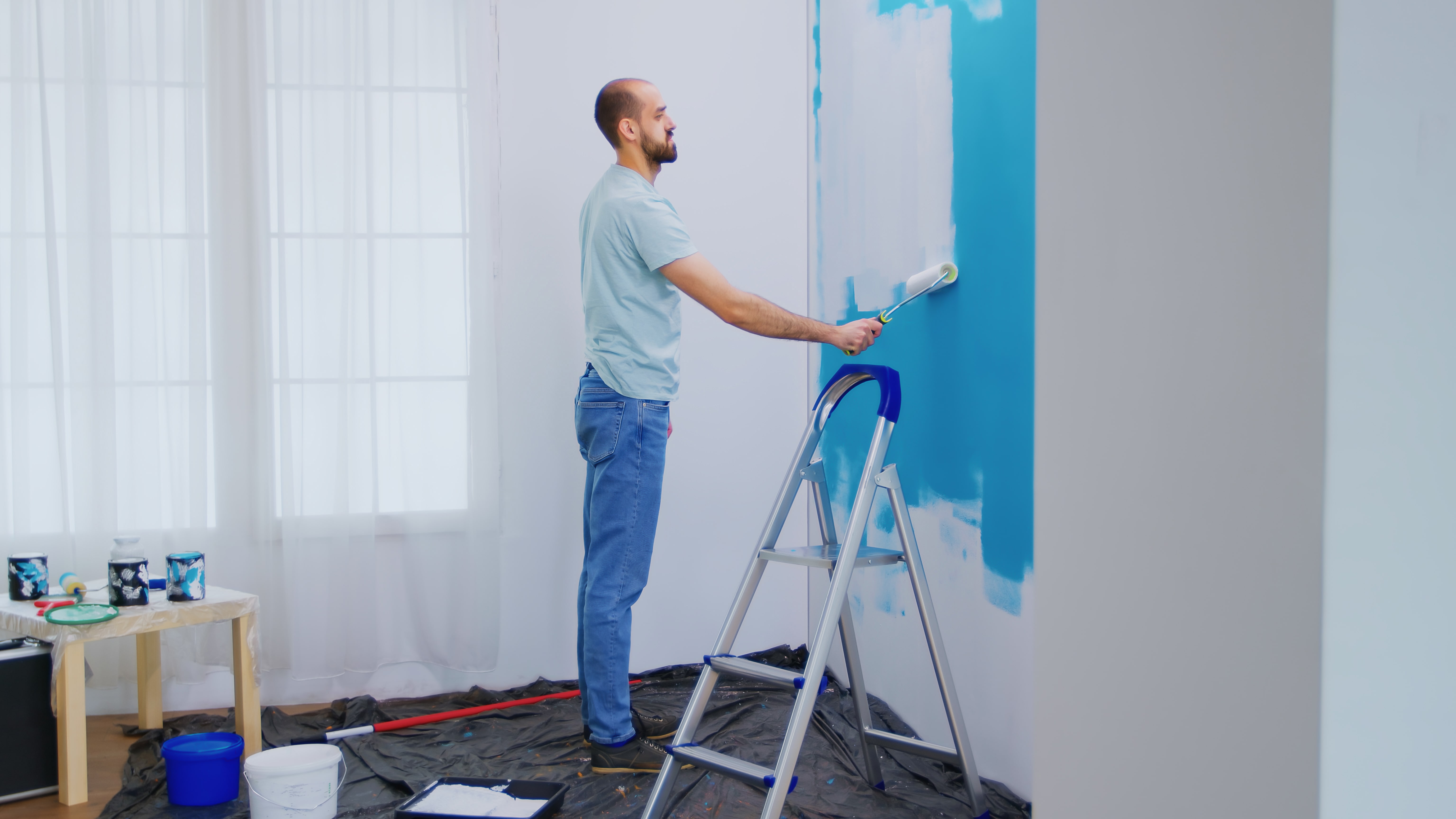 Handyman painting a wall with a paint roller