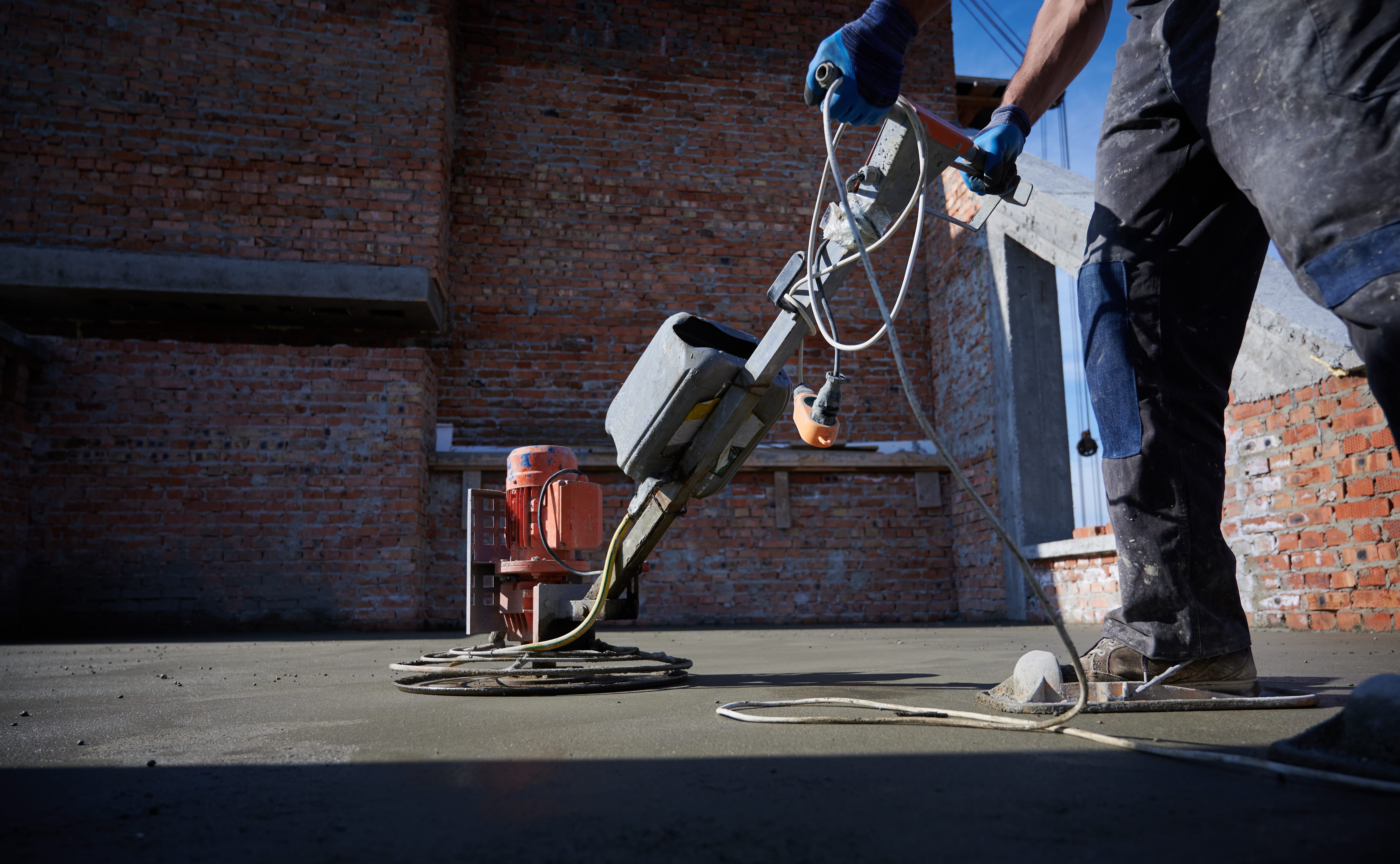 A man using modern equipment to clean outdoor cement in front of a brick wall