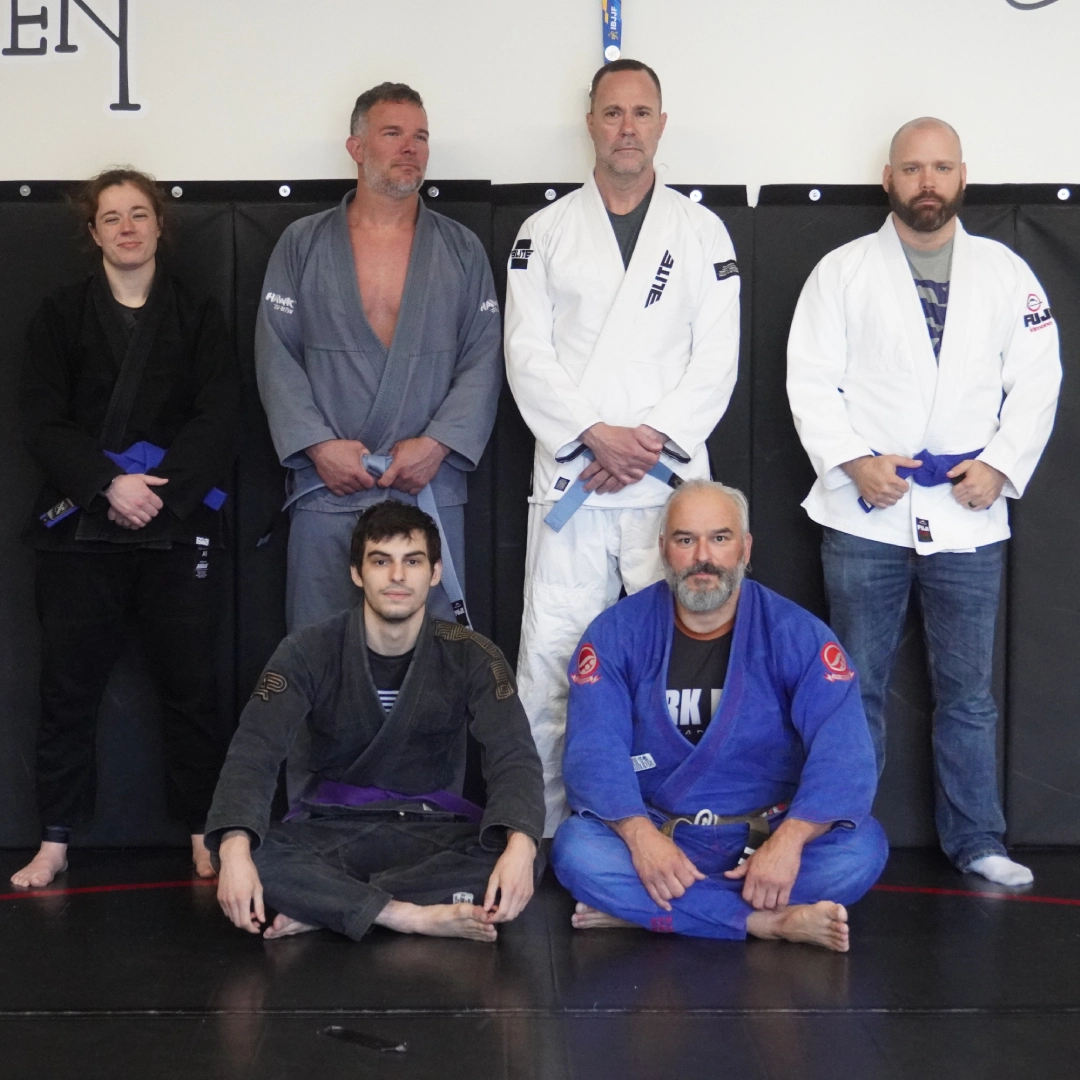 A group of people smiling and posing for a photo during a Brazilian Jiu Jitsu class at Horsemen BJJ in New Freedom, PA.